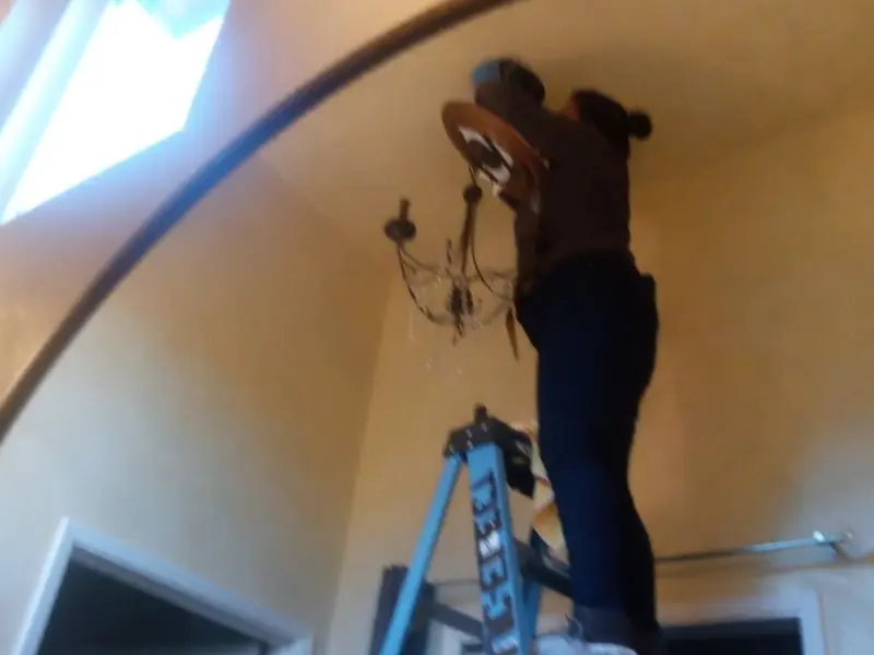 Electrician installing a chandelier in a Houston residence